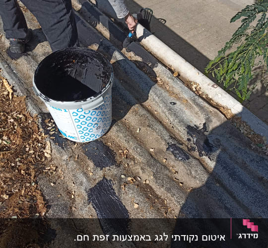 אדם מורח חומר איטום על גג עם מברשת
